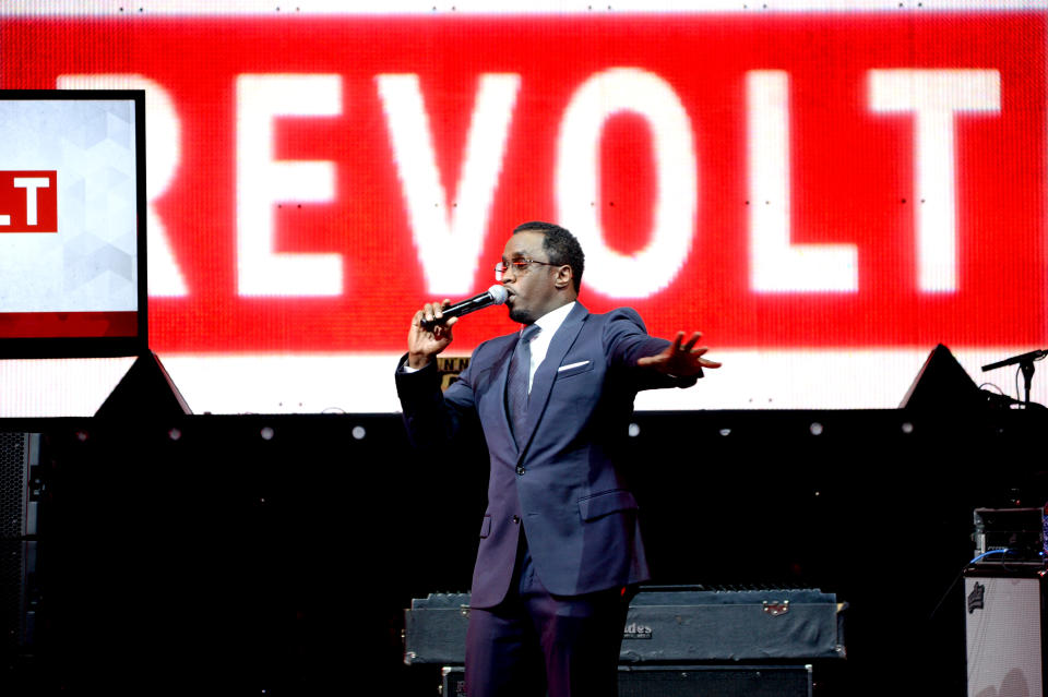 Combs habla por un micrófono frente a un telón de fondo con el logo de Revolt.