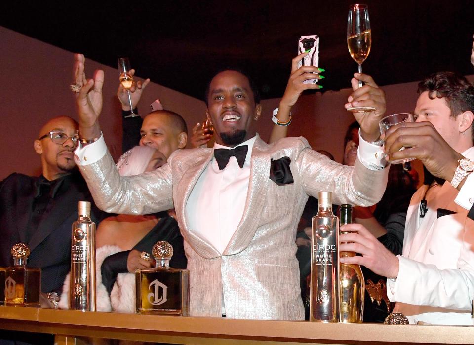 Sean Combs levanta una copa en su 50 cumpleaños.
